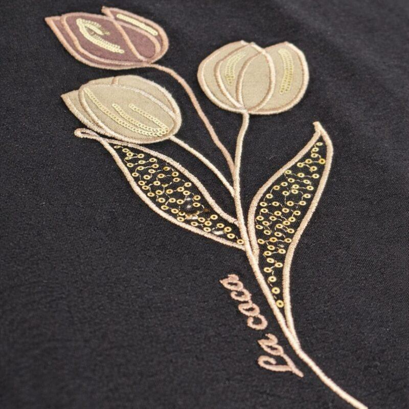 Zbliżenie haftu tulipanów z cyrkoniami na czarnej bluzce damskiej